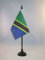 AZ FLAG - Drapeau De Table Tanzanie - 15x10 cm - Mini Drapeau Tanzanien De Bureau 100% Polyester Avec Hampe De 25cm Et Socle En Plastique Noir