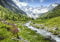 wandmotiv24 Fototapete Berge Alpen Wiese Bach, XXL 400 x 280 cm - 8 Teile, Wanddeko, Wandbild, Wandtapete, Wasser Schnee Wald Bäume Gras M6751