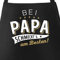 MoonWorks® Kochschürze Grill-Schürze für Männer und Frauen mit Spruch Bei Papa bzw Mama schmeckts am besten! Baumwoll-Schürze Küchenschürze schwarz unisize