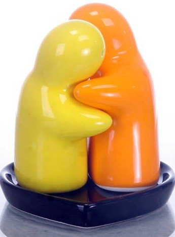 salt and pepper hugging salt and pepper shakers yellow and orange on a black heart tray