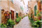 Wallario Outdoor-Poster für Garten oder Balkon Südländische Gasse mit Alten Häusern und grüner Oase, Motivbanner Größe: ca. 120 x 180 cm, Outdoor-Bild