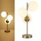 Alpinaluz Lámpara de Mesa de Acero Dorado – Diseño Elegante con Triple Pantalla de Bola de Cristal Opal Blanco Ø15cm – 3 Casquillos E27 – Iluminación Decorativa para Salón, Dormitorio u Oficina