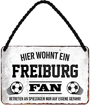 Hier wohnt ein Freiburg Fan Blechschild - Metallschild mit Kordel und Saugnapf - Fussball Fans Ultras Anhänger Begeisterte - Wanddeko Türdeko Man Cave Jugendzimmer Werkstatt Wohnzimmer - 18x12cm