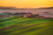 adrium Holz-Bild 110 x 70 cm: Toskana, sanfte Hügel bei Sonnenuntergang. Kreta Senesi ländliche Landschaft und Sonnenlicht. Grüne Felder, ein Bauernhof mit Bä(37763038)